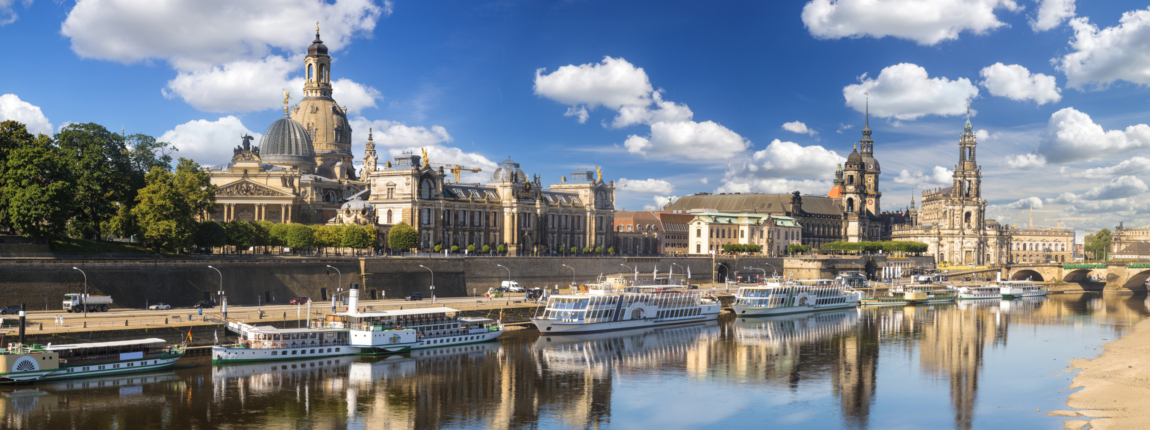 Panoramic view of Dresden's waterfront with historical buildings and boats along the river.